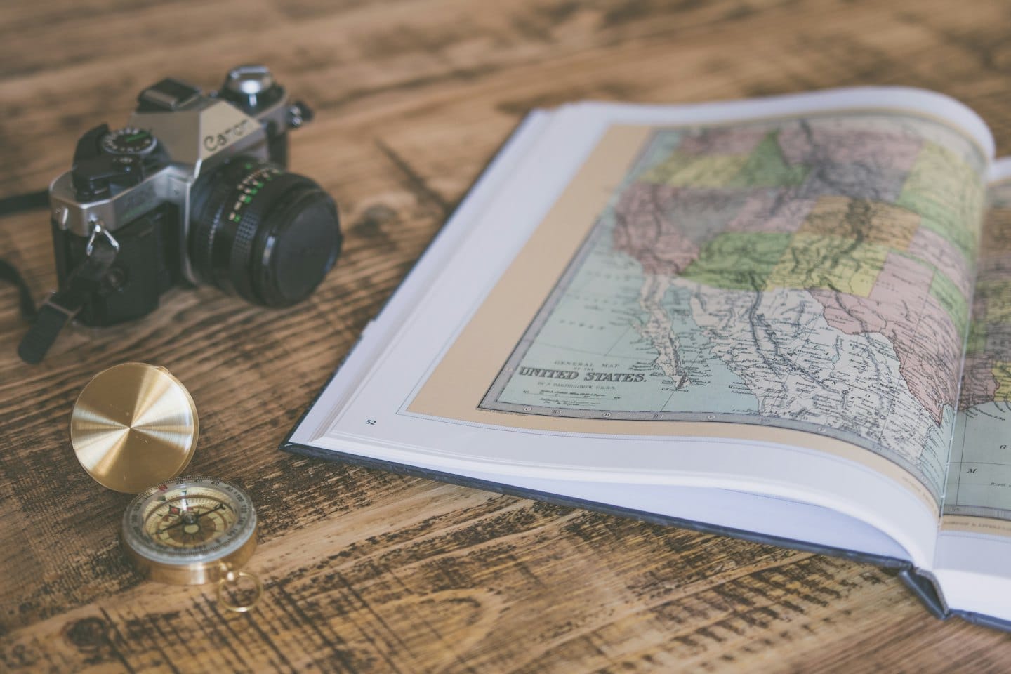 Vintage map, camera, and compass on a wooden table.
